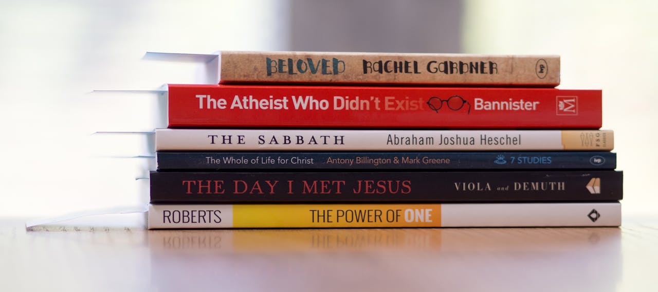 A stack of various books on a table, showcasing diverse titles and genres.